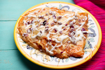 Mexican red enchiladas with melted cheese on turquoise background