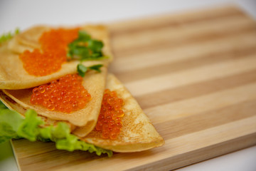 Pancake caviar on a wooden board isolated background