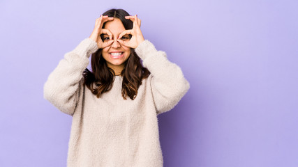 Young mixed race hispanic woman isolated showing okay sign over eyes