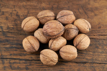 group of fresh raw walnuts on old wooden board background. rustic and detailed image.