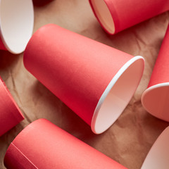 pile of disposable red paper cups on paper background. eco friendly concept. look from above. background backdrop