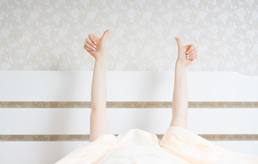 Awakening in a good mood concept with female hands from under the blanket