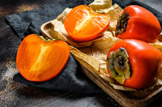 Ripe  Persimmon on a wooden tray. Dark background. Top view