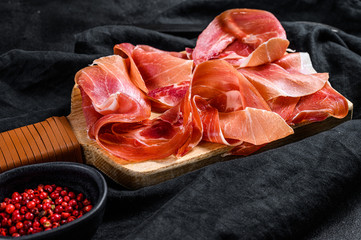 prosciutto crudo, italian salami, parma ham. Antipasto plate. Black background, top view.