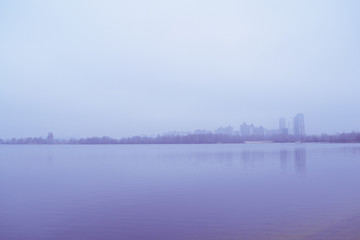 View across the lake in the fog on the city in the distance