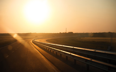 An early morning road in orange color lighted by a sunrise.