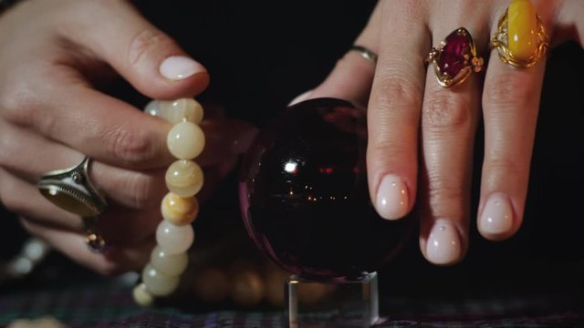 Close-up of of fortune teller's fingers rotate crystall ball.  Magician, black magic and prophecy concept