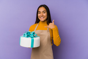 Young asian woman holding a cake isolated showing a mobile phone call gesture with fingers.