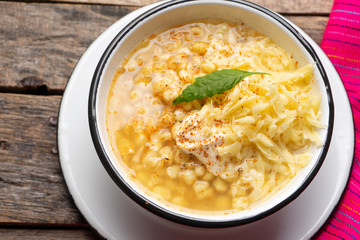 Mexican corn grain boiled also called esquites with cheese and mayonnaise on wooden background