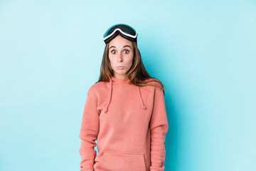 Young skier woman isolated shrugs shoulders and open eyes confused.