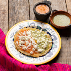 Mexican memela with green and red sauce on wooden background