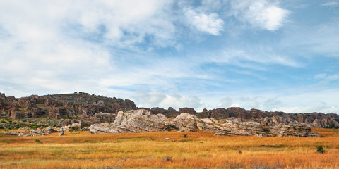 Typical scenery at Isalo national park as seen from main road - small rocky hills with fields of grass in foreground