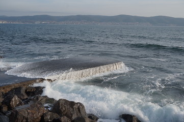 Sea water on a stone slab, an incident wave is breaking on stones, water splashes.