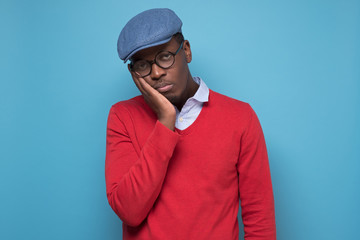 frican American college student in red sweater and blue hat is tired and bored