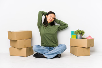 Young chinese woman moving to a new home stretching arms, relaxed position.