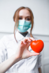 Close up photo Two red-hair cardiologist holding a red toy heart. An approximate photo of the hands...