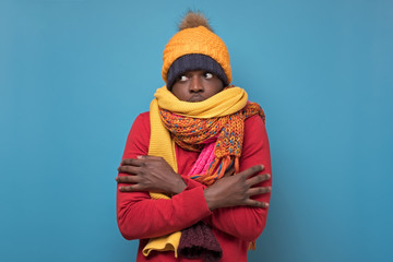 african american funny man in several hats and scarfs on blue background.
