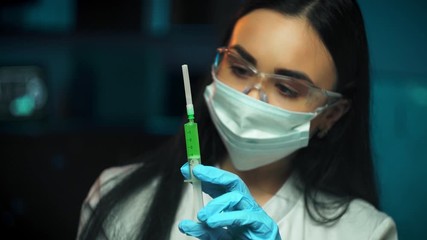 lab technician in glasses holding a syringe on a blue background science - Powered by Adobe
