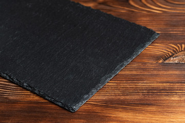 Crockery slate, black stone on a wooden background.