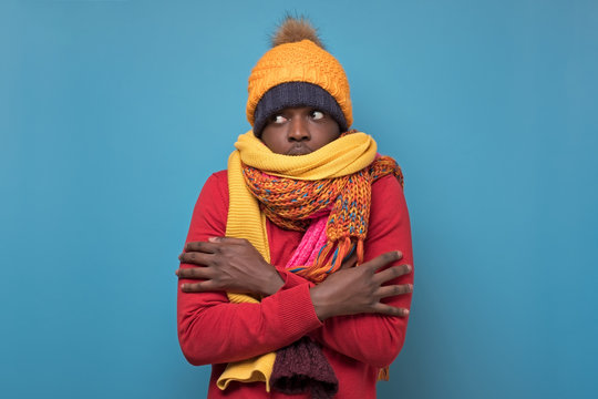 African American Funny Man In Several Hats And Scarfs On Blue Background.