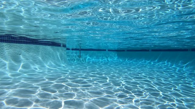 Moving underwater view of sunlight patterns in clean suburban swimming pool.