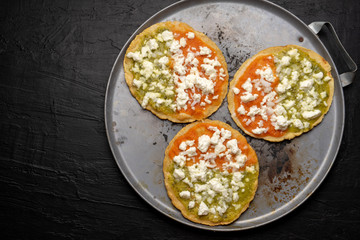 Mexican memela with green and red sauce on dark background