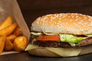 Burger on the slate utensils next to the potatoes.