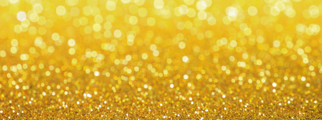 Golden glittering background, horizontal banner, panorama. Sparkle glitter texture with the bokeh and the lights, shiny metal gold foil