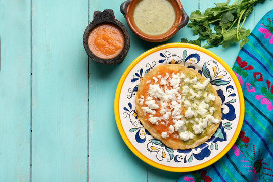 Mexican memela with green and red sauce on turqouise background