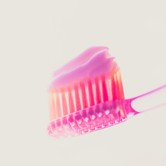 Pink plastic toothbrush with strawberry toothpaste on an isolated background.