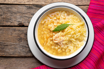 Mexican corn grain boiled also called esquites with cheese and mayonnaise on wooden background