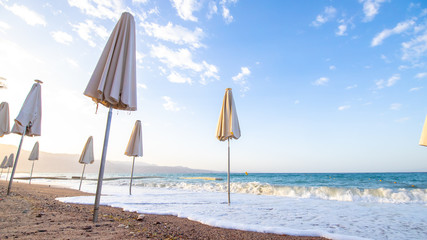 sunrise on the beach. beautiful summer scenery. rocks on the sand. calm waves on the water. clouds on the sky. wide panoramic view