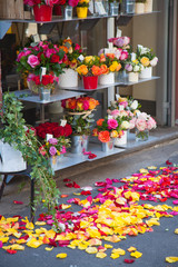 Fototapeta na wymiar Various bright bouquets on a flower shop window. Rose petals lie on the pavement. Gift. Birthday, holiday, international women's day, mother's day