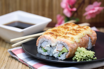 Sushi roll set on a plate, with sushi sticks on wooden background.