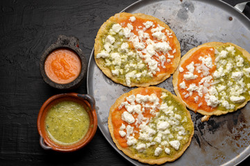 Mexican memela with green and red sauce on dark background