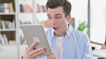 Excited Young Man in Surprise Looking on Tablet