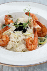 Shrimp risotto with ginger and lemongrass, decorated with black caviar close up