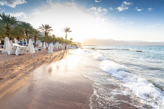 sunrise on the beach. beautiful summer scenery. rocks on the sand. calm waves on the water. clouds on the sky. wide panoramic view