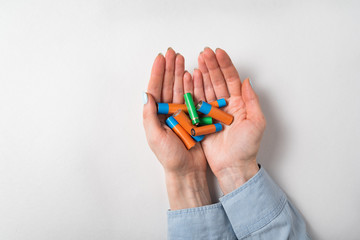 A lot of batteries in women hands on white background. Handful of alkaline accumulators.