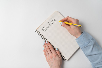 New Life Words written in a notebook on a white background. Top view of female hand with copybook.