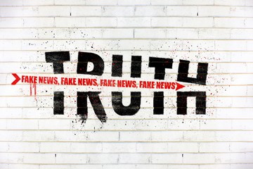 The word truth with an arrow of fake news painted on old white wall, Truth being destroyed by fake...
