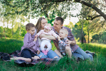Happy large family picnic in the Park. Family outdoor recreation. Young parents and three children.
