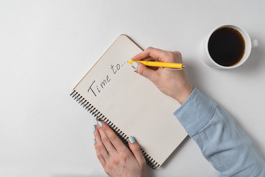 Time to written on notebook over white background. Female hands the Notepad and cup of coffee