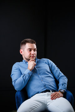 Fellow businessman in blue shirt and white trousers on a black background