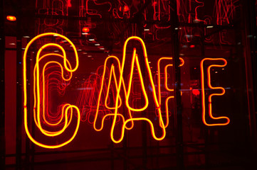 Cafe sign in bright yellow neon letters on the red glass wall