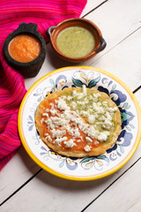 Mexican memela with green and red sauce on white background