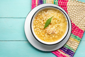 Mexican corn grain boiled also called esquites with cheese and mayonnaise on turquoise background