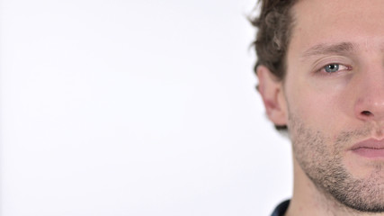 Fototapeta premium Close up of Half Face of Serious Young Man on White Background