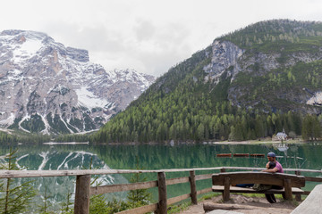 Loving couple on Lago di Braies, impressive green lake, which reflects the high snowy mountains, surrounded by abundant green vegetation