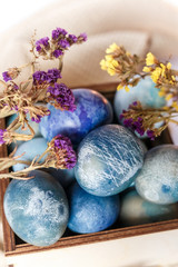 Easter colored eggs in a wooden box on white background. Easter eggs and spring flowers. Holiday pattern.